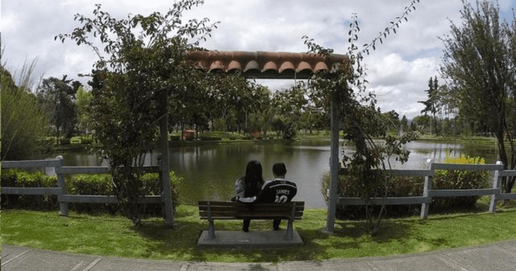 Imagen de una pareja de enamorados sentados en una banca a la orilla del lago en el Parque El Lago de Bogotá