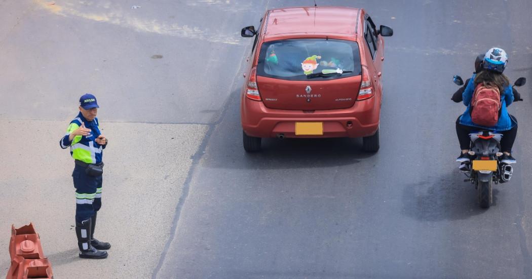 Foto que muestra un vehículo y una moto andando por una calle 