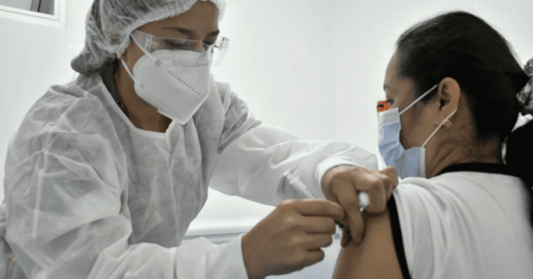 Imagen de una enfermera vacunando a una mujer que se encuentra sentada.