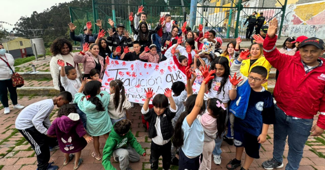 Imagen de varias personas alzando las manos pintadas de rojo