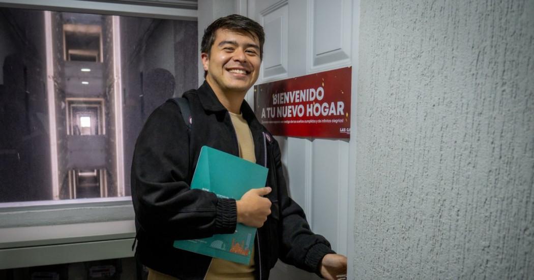 Foto que muestra una persona sonriente abriendo una puerta