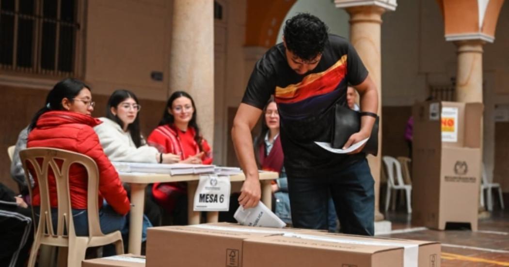 Hombre joven depositando su voto en una urna.