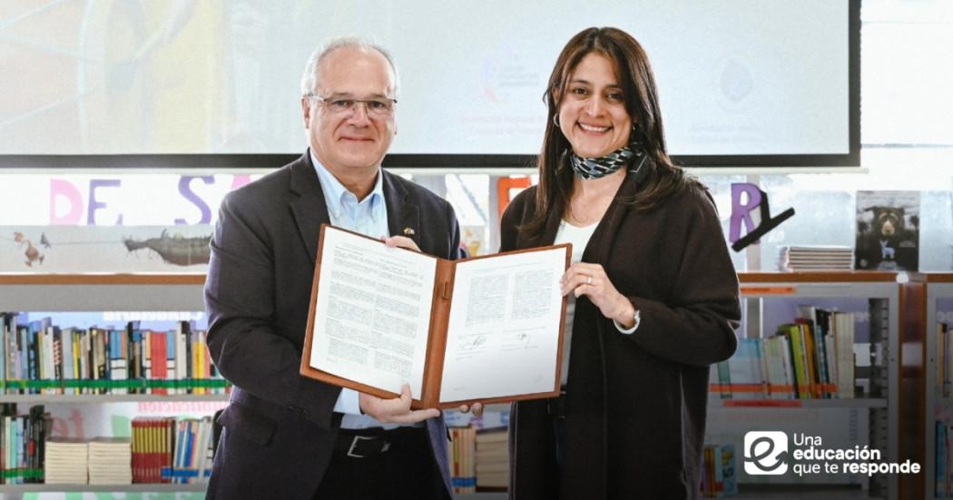 Foto que muestra dos personas sonriendo con un documento en las manos