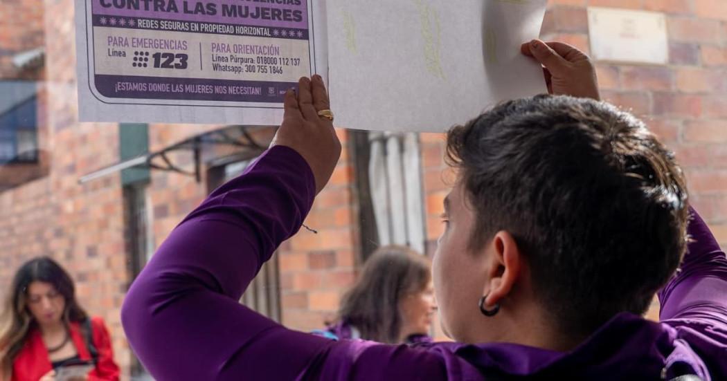 Mujer con un cartel sobre rutas de atención para mujeres víctimas de violencia.