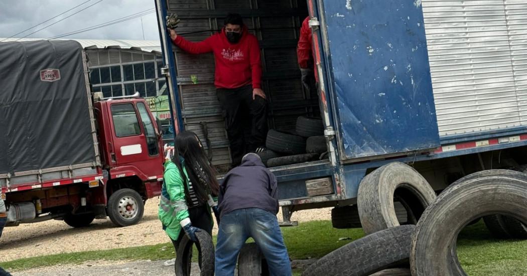 Foto que muestra personas subiendo llantas en desuso en un camion 