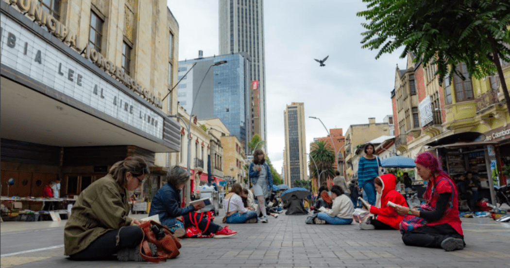 Imagen panorámica de la carrera séptima donde varias personas leen sentados en la vía.
