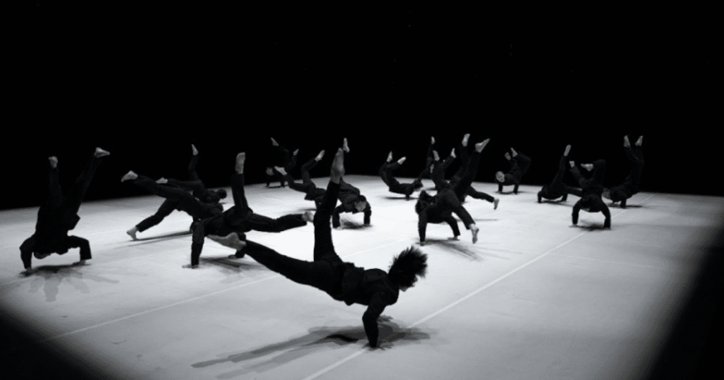 Imagen de los bailarines en la puesta en escena, ellos visten trusas negras