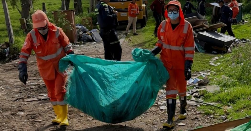 Foto que muestra personas levantando una bolsa con residuos