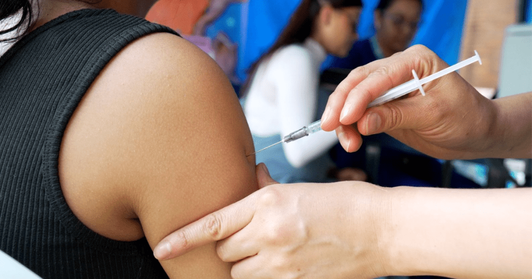 Foto de una enfermera colocando una vacuna en el hombro de una persona