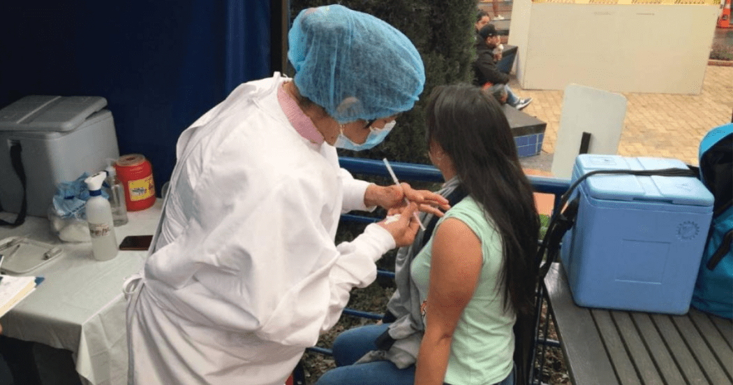 Foto de una enfermera colocando una vacuna en el hombro de una persona