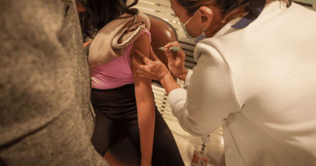 Foto de una enfermera colocando una vacuna en el hombro de una persona