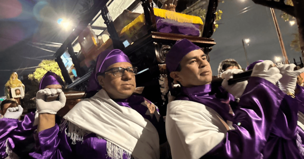 Imagen de dos hombres cargando un imagen de jesucristo