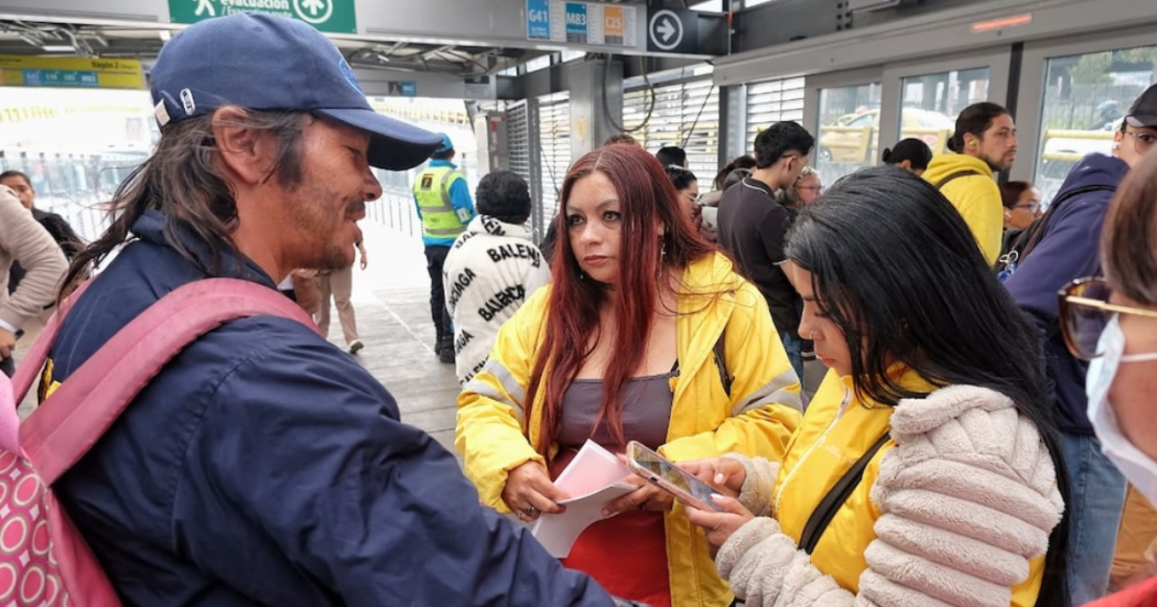 Imagen de una funcionaria hablando con un habitante de calle en una estación de TransMilenio