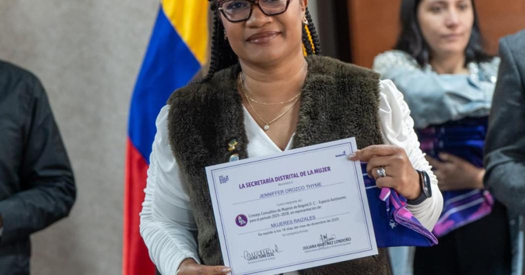 Mujer posando con un certificado de un programa de la Secretaría de la Mujer