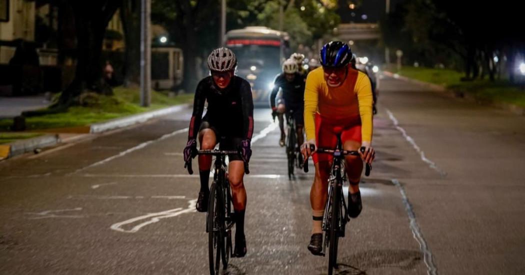 Dos ciclistas pedaleando en Bogotá de noche