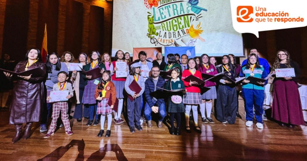 Foto que muestra personas reunidas en una tarima con diplomas en la 
