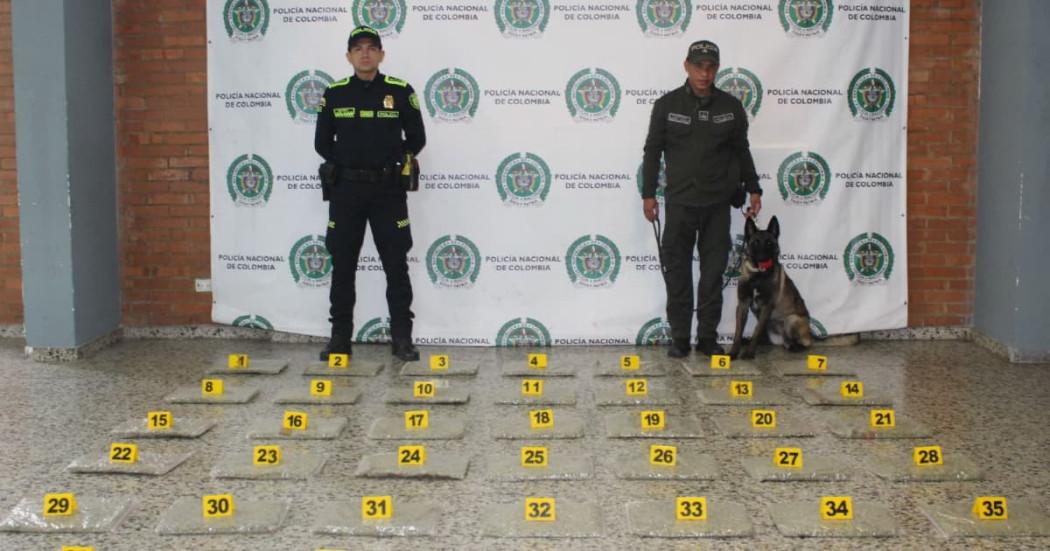 Uniformados y perro anitinarcótico frente a droga incautada en el aeropuerto El Dorado.