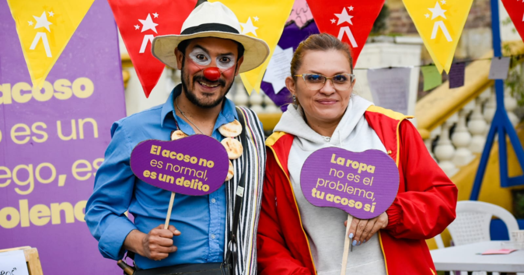 Foto de dos funcionarios del Distrito con carteles en contra del acoso