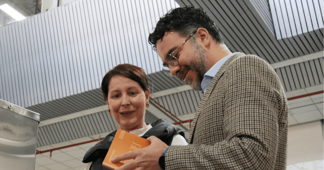 Secretario general lee libro junto a usuaria de la red cade