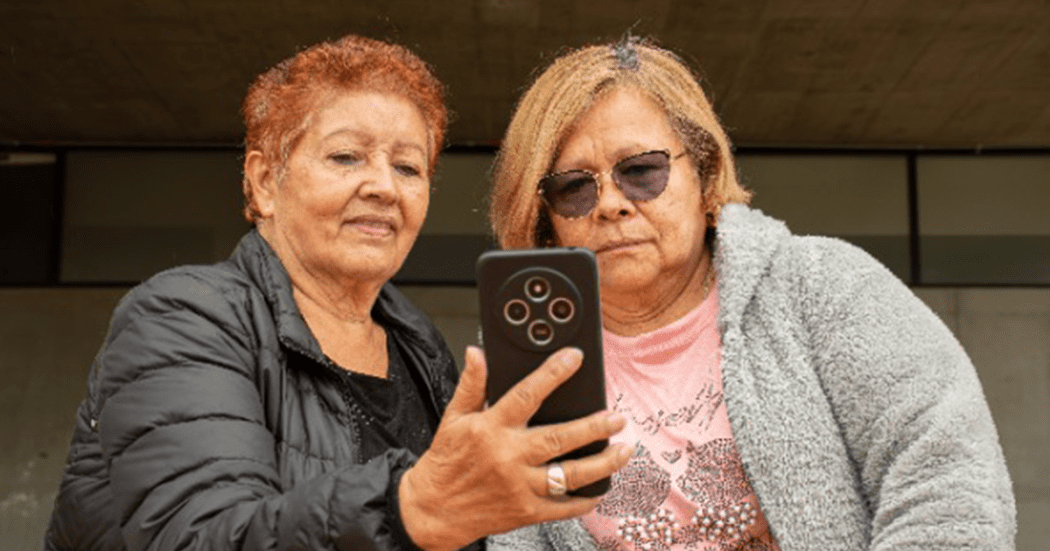 Imagen de dos mujeres adultas mayores viendo un celular