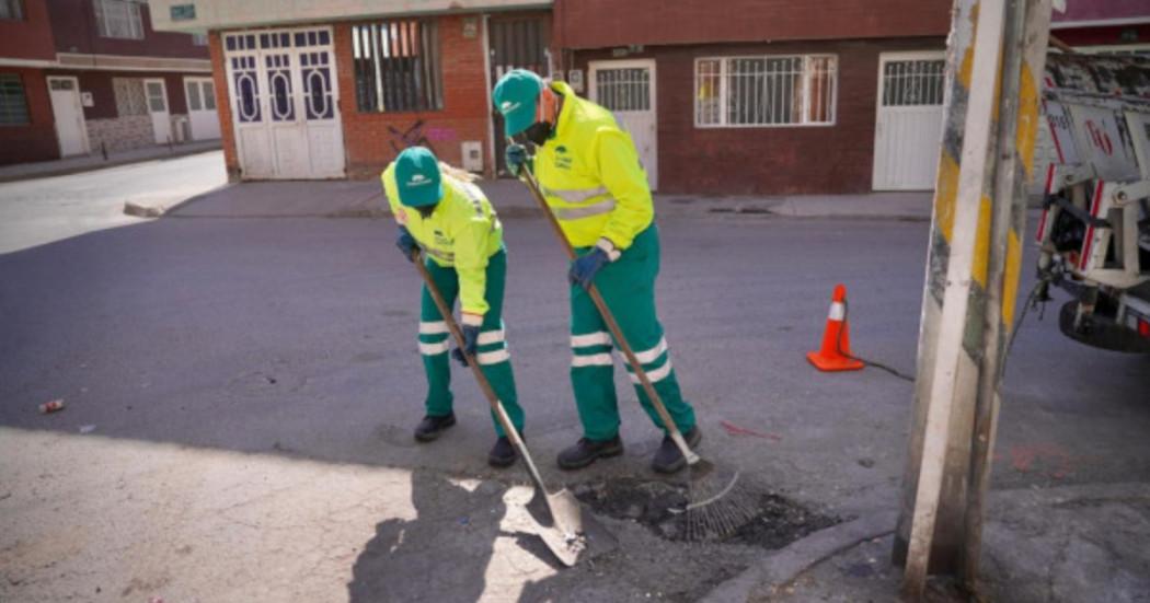 Foto que muestra dos personas barriendo la calle 