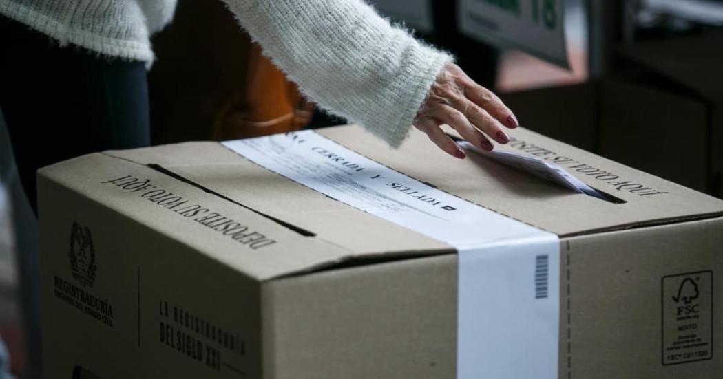 Persona depositando su voto en una urna.