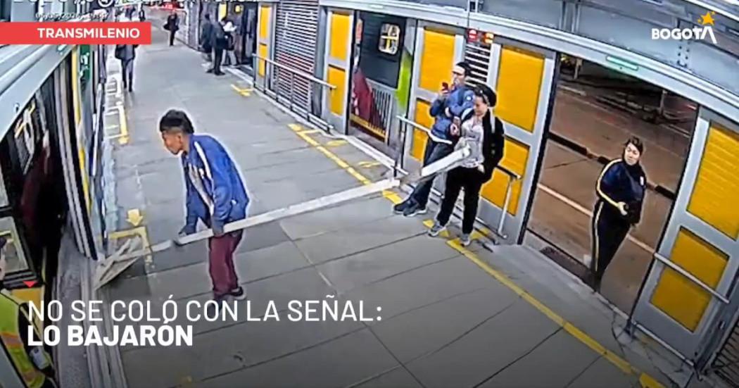 Imagen de cámara de seguridad en la que se ve a hombre intentando subirse a un bus de TransMilenio con una craga no permitida.