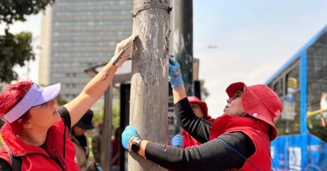 Funcionarios del DADEP limpiando un poste de luz de publicidad no permitida.