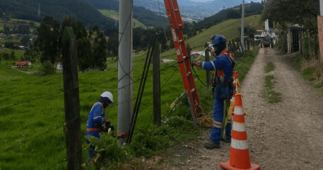 Imagen de varios técnicos de Enel realizando mantenimiento a un poste de energía.