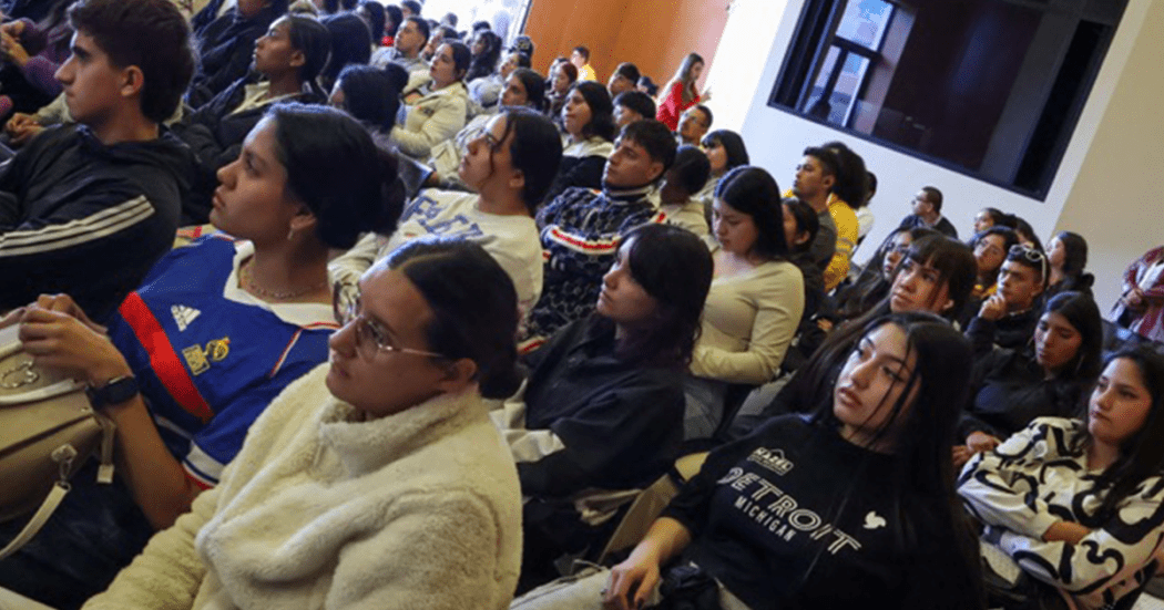 Imagen de jóvenes sentados escuchando a una persona