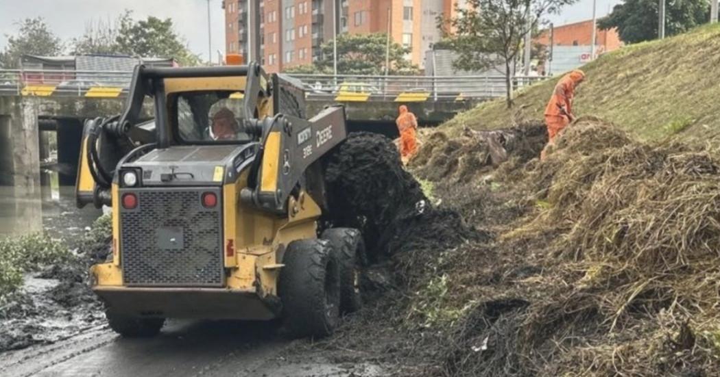 Foto que muestra un carro recolector y personas levantando residuos en un canal