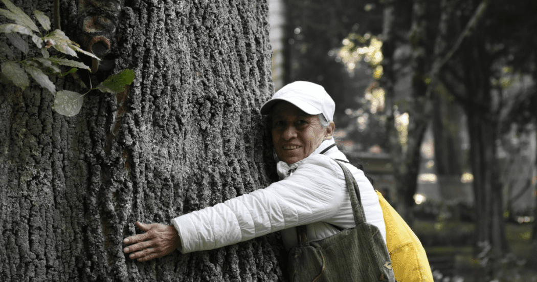 Foto de un hombre abrazando un arbol 