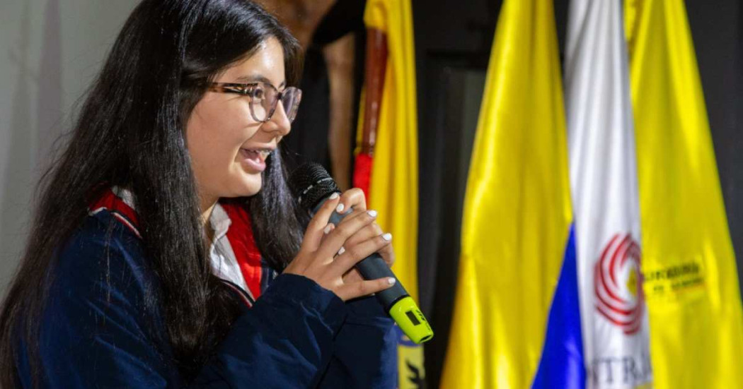 Foto que muestra una estudiante hablando con un microfóno en la mano