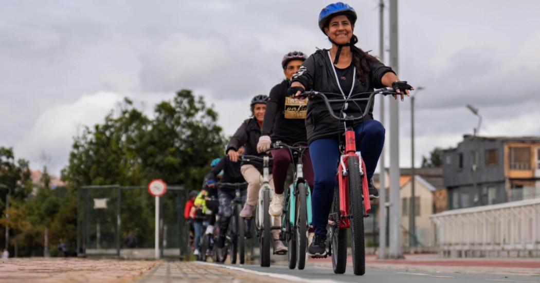 Grupo de mujeres ciclistas pedaleando en ciclovía de Bogotá con cascos alineados