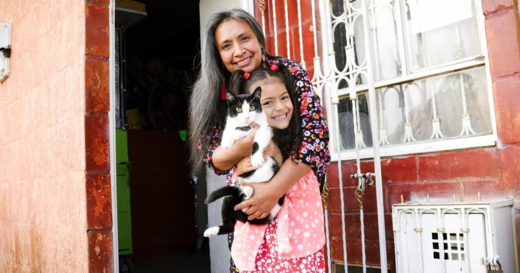 Imagen de una mujer abrazando a una niña que está cargando a un gato.