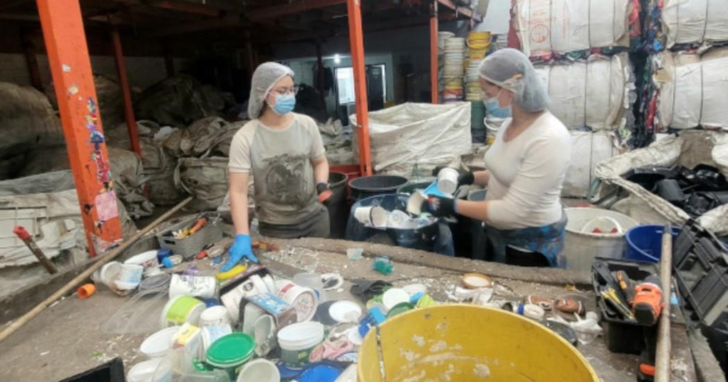 Foto que muestra dos personas con gorros y tapabocas reciclando 