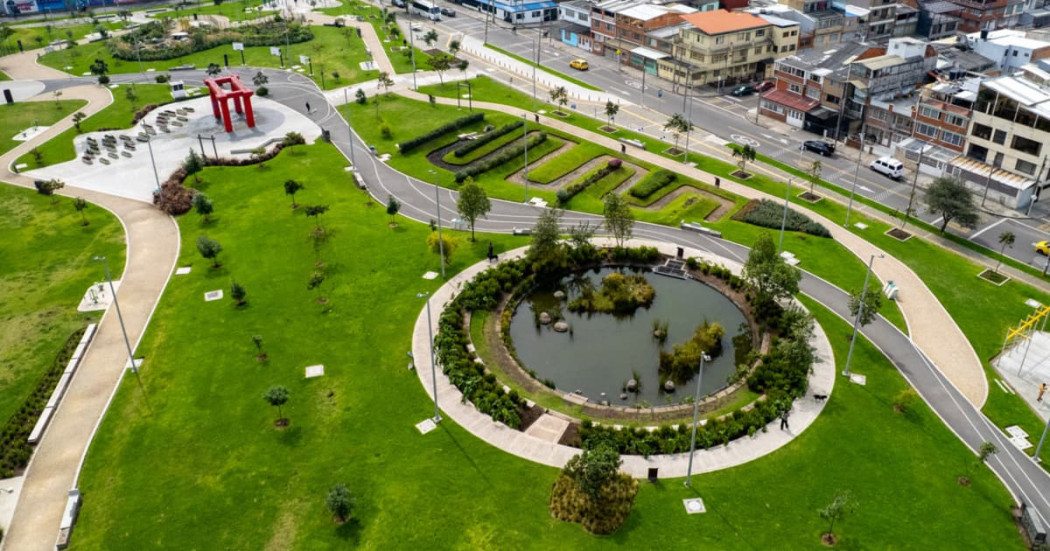 Vista aérea parque urbano de Bogotá con lago circular senderos áreas verdes y viviendas