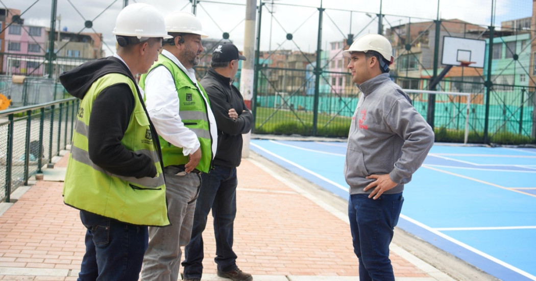 Foto que muestra cuatro personas con casco blanco hablando en un parque