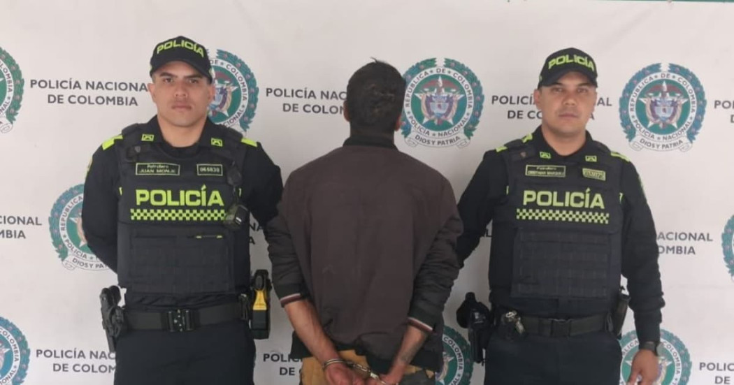 Hombre capturado, de espaldas, en medio de dos policías.