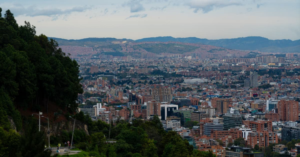 Panorámica de Bogotá con edificios, cerros orientales y cielo parcialmente nublado