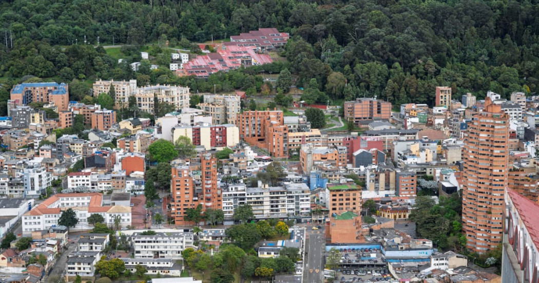 Panorámica urbana de Bogotá con edificios residenciales y cerros verdes al fondo