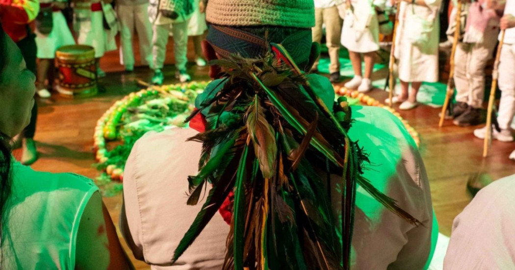 Imagen de señor de espalda con banda de plumas en ritual de fuego
