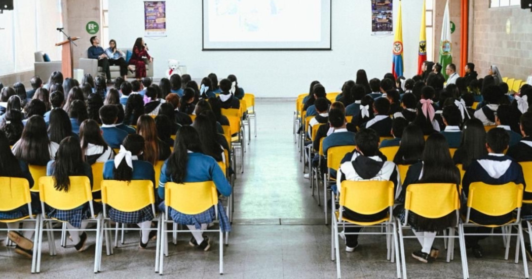 Foto que muestra estudiantes de colegio sentados en un auditorio