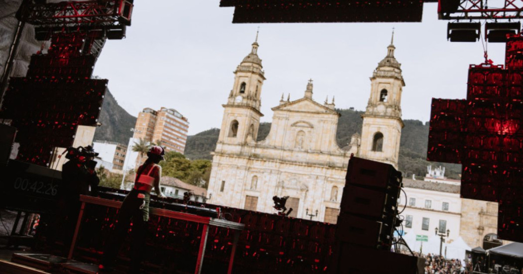 Imagen de una mujer dj tocando una consola al frente de la iglesia en la Plaza de Bolivar