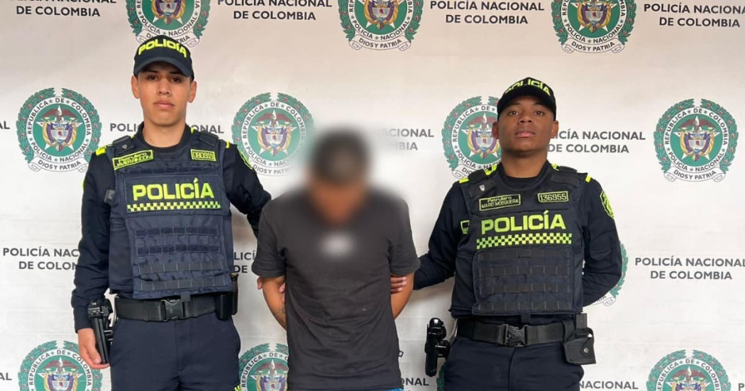 Hombre capturado por homicidio en medio de dos policías.