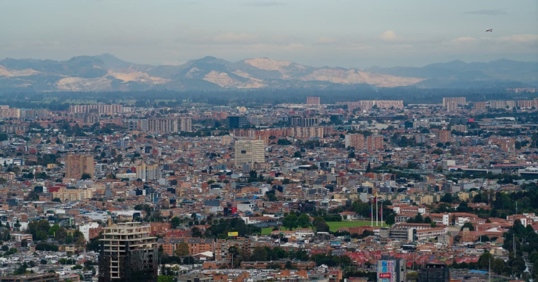 Vista panorámica de Bogotá con edificaciones extensas, montañas lejanas y cielo despejado
