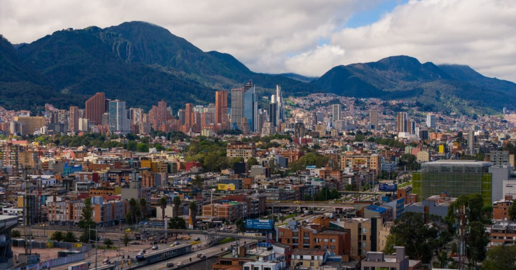 Vista panorámica de Bogotá con edificios residenciales, zona financiera y cerros orientales bajo cielo parcialmente nublado