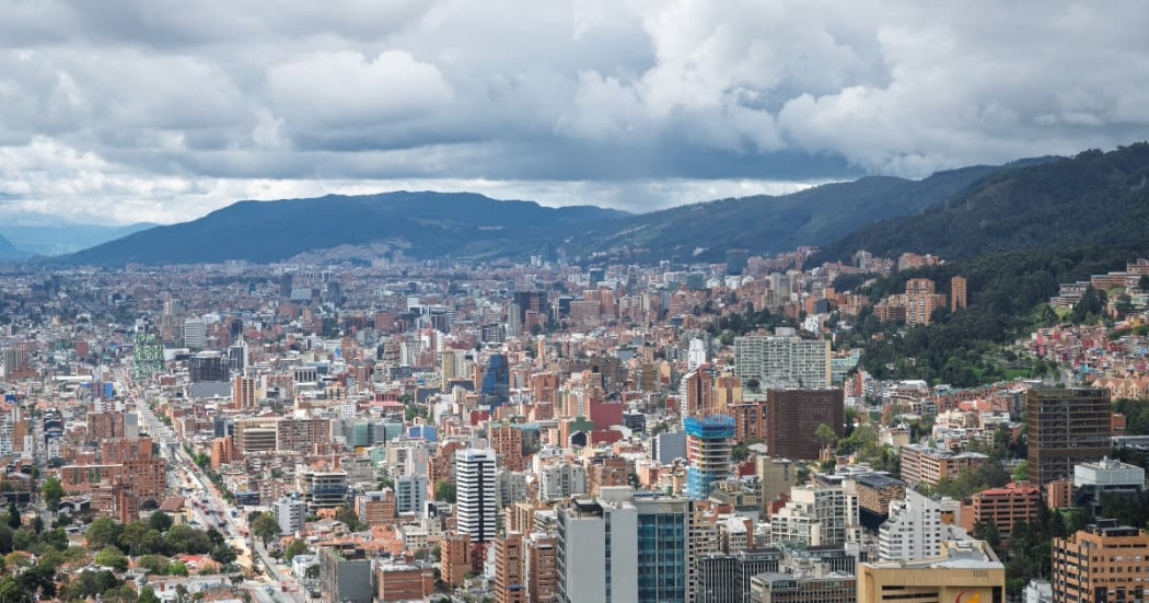 Vista panorámica de Bogotá con edificaciones, montañas orientales y cielo nublado amplio
