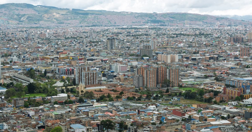 Vista panorámica de Bogotá con barrios, montañas al fondo y cielo nublado