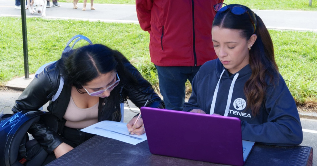 Foto que muestra dos mujeres sentadas escribiendo en un papel sobre una mesa